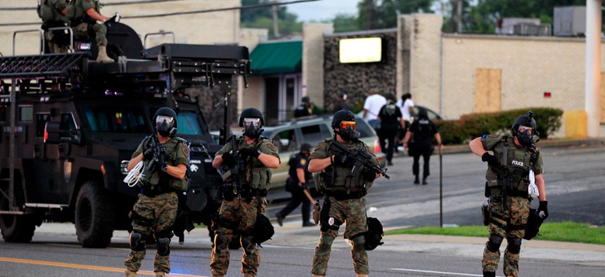 Police in riot gear work near crowds gathering in Ferguson Monday evening.