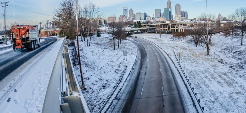 In this file photo, a snow plow at left treats a highway overpass near Charlotte's Uptown central business district.