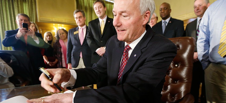 Arkansas Gov. Asa Hutchinson, a Republican, prepares to sign a bill providing a state income tax cut earlier this month. Other states also are considering tax cuts for low- and middle-income earners.