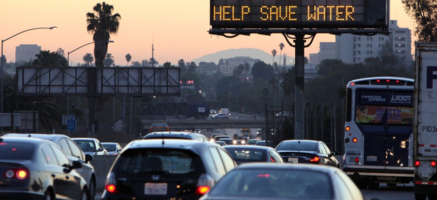 Morning traffic passes a sign in Los Angeles in July warning of drought.