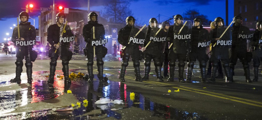 Police stand guard Monday, April 27, 2015, after rioters plunged part of Baltimore into chaos, torching a pharmacy, setting police cars ablaze and throwing bricks at officers.
