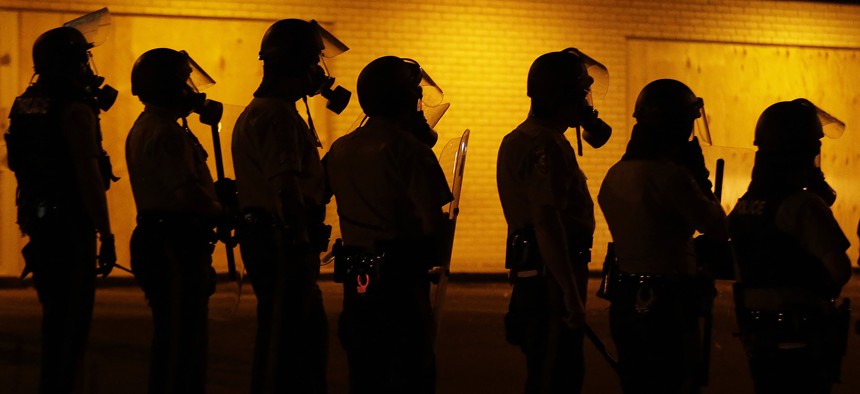Police wait to advance after tear gas was used to disperse a crowd during a protest for Michael Brown, who was killed by a police officer on Aug. 9, in Ferguson, Mo. 