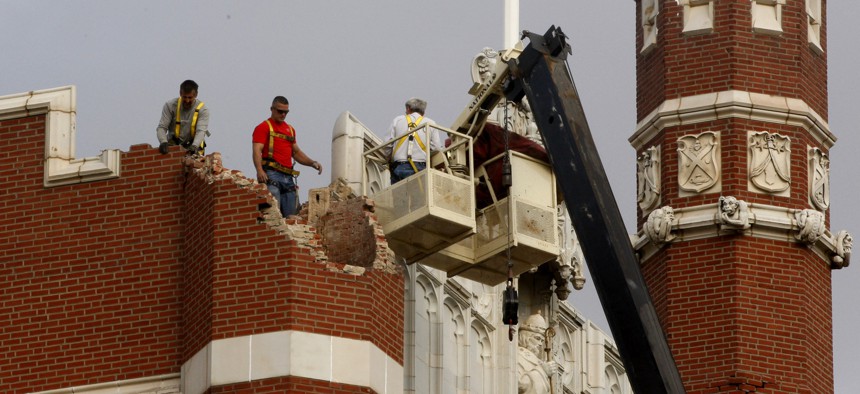 Maintenance workers inspect the damage to one of the spires on Benedictine Hall at St. Gregory's University in Shawnee, Okla., following an earthquake in 2011.