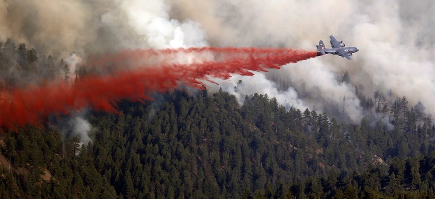A military C-130 drops a load of fire retardant on a wildfire near Pine, Colo., on Wednesday, June 19, 2013.
