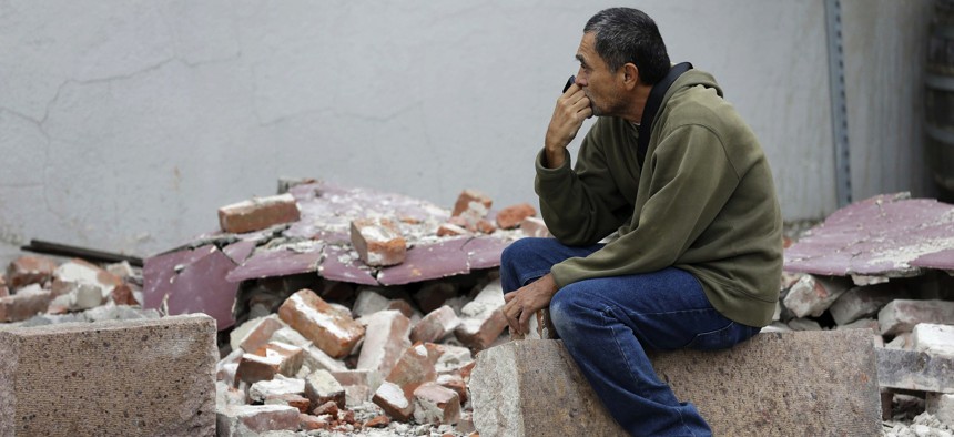Ron Peralez, of Vacaville, Calif., sits on rubble and looks at earthquake-damaged buildings Monday, Aug. 25, 2014, in Napa, Calif.