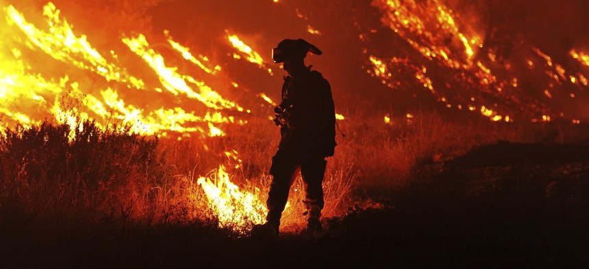 In this Aug. 3, 2015, file photo CalFire firefighter Bo Santiago lights a backfire as the Rocky fire burns near Clearlake, Calif.