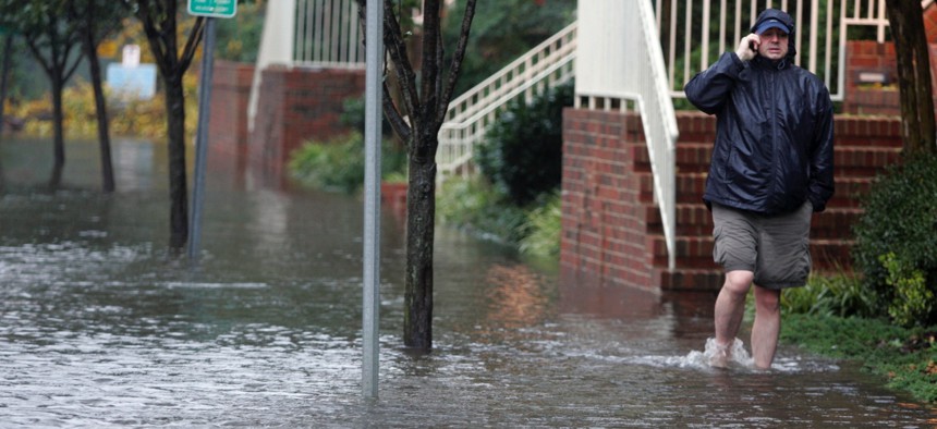 A resident talks on his cell as he walks through a flooded street in Norfolk, Va., on Nov. 13, 2009, as the area was hit by remnants of Tropical Storm Ida.