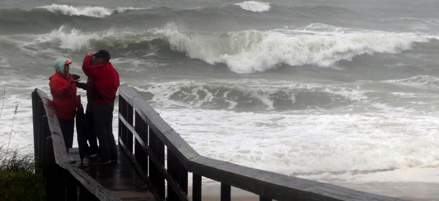 People watch the waves in a rainstorm at Atlantic Ocean at Carolina Beach, N. C., Friday, Oct. 2, 2015. Millions along the East Coast breathed a little easier Friday after forecasters said Hurricane Joaquin would probably veer out to sea instead of joinin