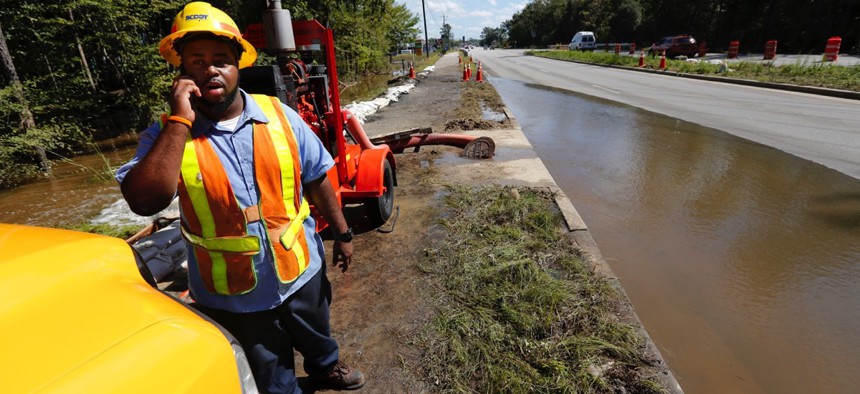 George Jenkins, with the South Carolina Department of Transportation, calls to officials asking whether to close Dorchester Road as floodwaters caused by high tide begin to flood the road again at Sawmill Branch Canal in Summerville, S.C., Thursday, Oct. 