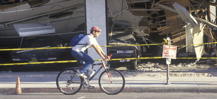 A cyclist rides by a destroyed car dealership in Santa Monica, Calif., after the Northridge earthquake in 1994.