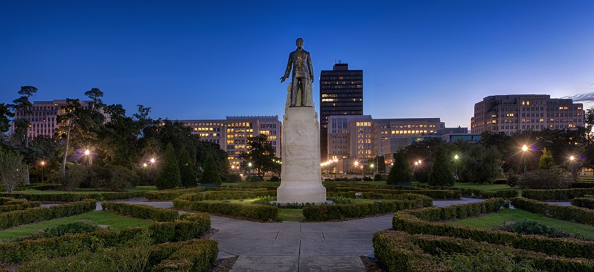 A statue and grave site of Huey Long on the grounds of the Louisiana State Capitol building at night in Baton Rouge, Louisiana.