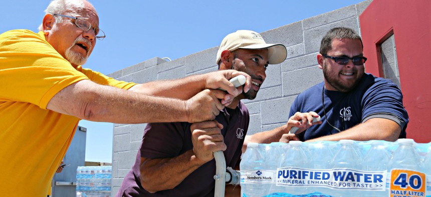 Leo Block, left, Matari Phason, center, and Brian Juarez, right, push part of a shipment of 20,000 water bottles donated by Yellow Cab of Phoenix to Central Arizona Shelter Services, Arizona's largest homeless shelter. 