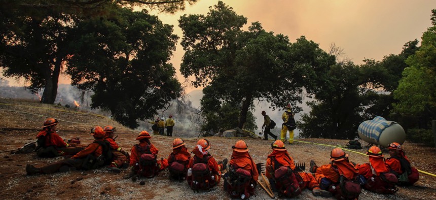 Members of hand crew rest on a hillside near Placenta Canyon Road as a wildfire burns in Santa Clarita, California, on Sunday.