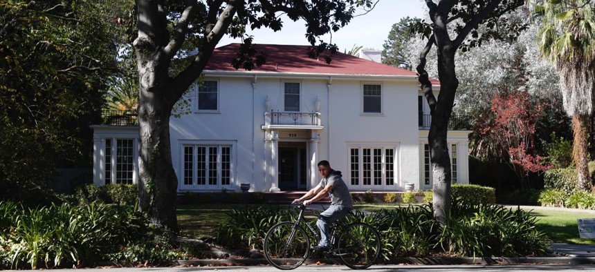 A man cycles past a large home in Palo Alto, California.