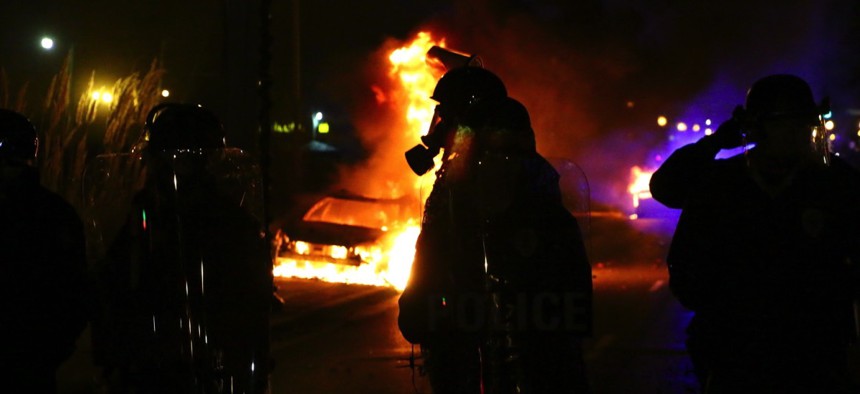 A police officer standing amid flames after riots broke out in Ferguson, Missouri on November 24, 2014.