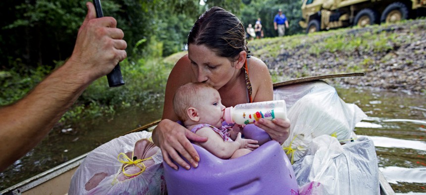 Danielle Blount and her baby wait to be rescued from floodwaters by members of the Louisiana Army National Guard near Walker, La.
