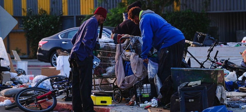 Homeless men sort through their belongings on a traffic island near downtown Los Angeles.