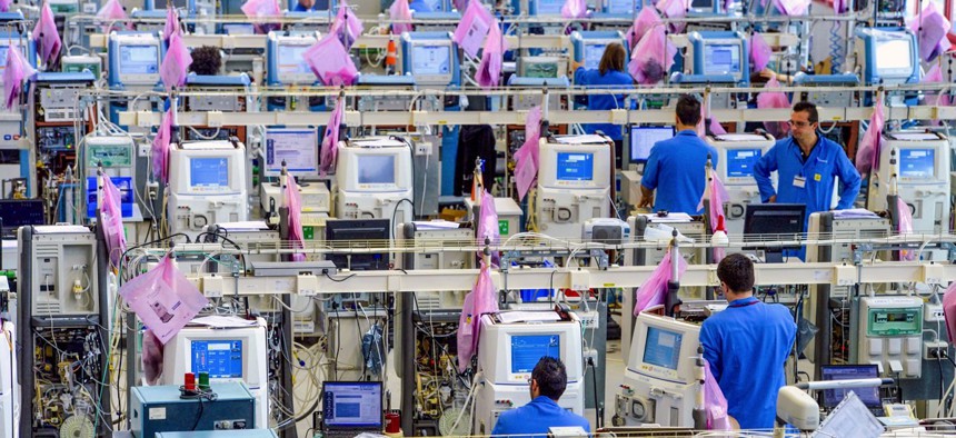 Factory workers assemble medical devices.