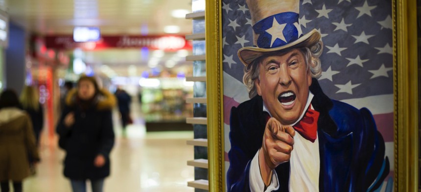 People walk past a caricature picture of U.S. President Donald Trump on sale in a shopping mall in Moscow, Russia.