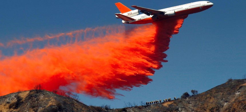 A DC-10 airplane tanker drops fire retardant to battle a wildfire in the San Gabriel Mountains in Azusa, Calif.