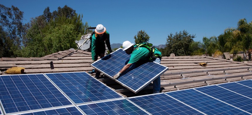 Two workers install solar panels on home in Oak View, Southern California.