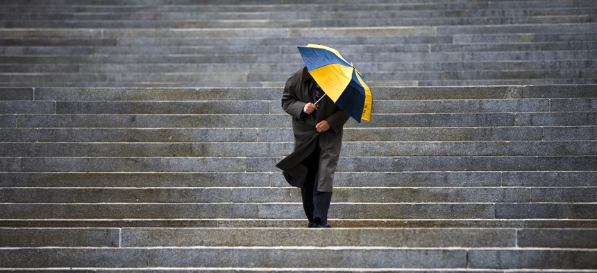 A man shields himself from the rain as he walks down the steps of the Pennsylvania state Capitol, in Harrisburg, in 2014.