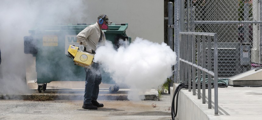 A Miami-Dade County mosquito control worker sprays around a school in the Wynwood area of Miami on Monday, Aug. 1, 2016.