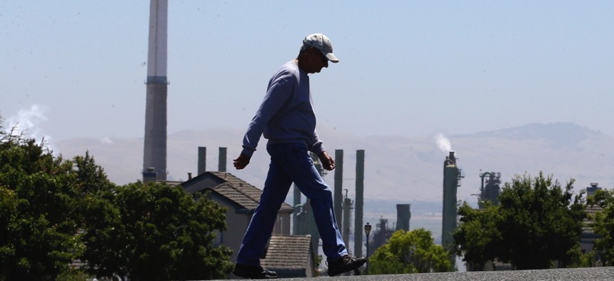 The stacks from the Valero Benicia Refinery in California are seen as a pedestrian walks in a nearby neighborhood.