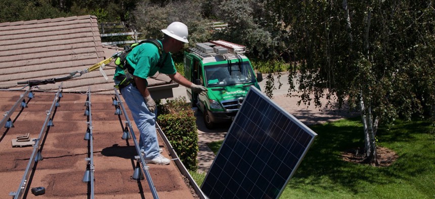 A worker installs solar panels on a home in Oak View, California. 