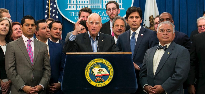 Gov. Jerry Brown, center, flanked by lawmakers from both sides of the aisle, speaks of the passage of a pair of climate change measures on Monday in Sacramento, Calif.