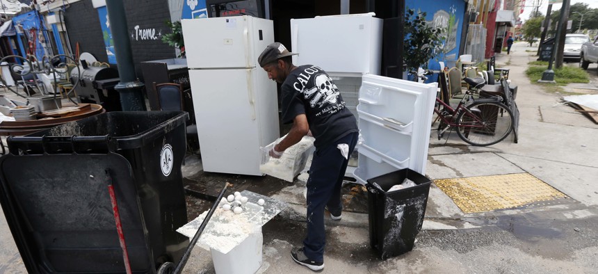 A worker throws out food from refrigerators pushed out to the curb, in the aftermath of flooding from the past weekend's rain storms, at the Treme Market and Restaurant.