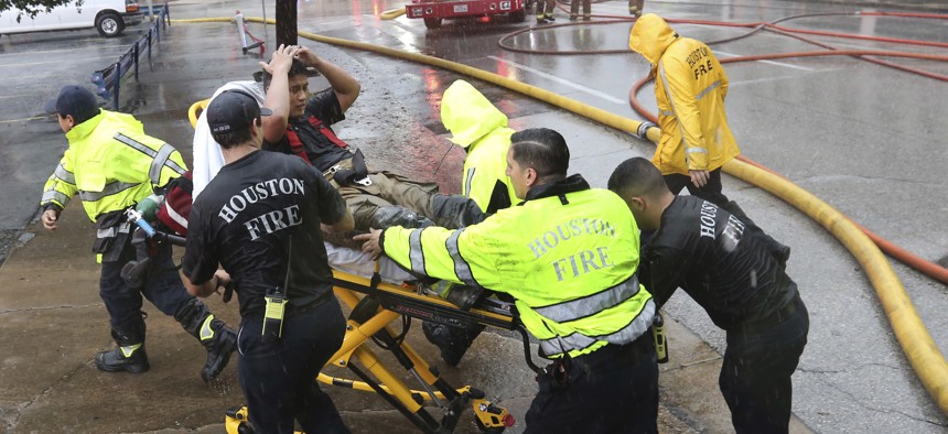 Rain from Tropical Storm Harvey falls as a firefighter is wheeled to a waiting ambulance after he became fatigued while fighting an office building fire in downtown in Houston, Texas, Monday, Aug. 28, 2017.