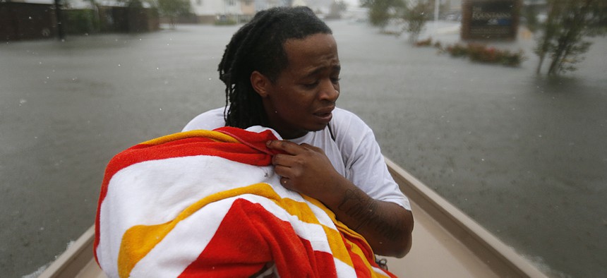 Demetres Fair holds a towel over his daughter Damouri Fair, 2, as they are rescued by boat by members of the Louisiana Department of Wildlife and Fisheries and the Houston Fire Department on Monday in Houston.