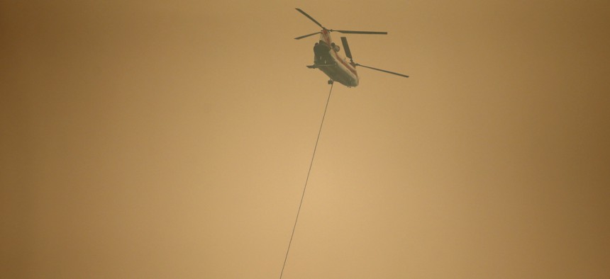 A helicopter with a water bucket flies through dense smoke near Stevenson, Wash., Wednesday, Sept. 6, 2017, as it works to battle the Eagle Creek wildfire on the Oregon side of the Columbia River Gorge.