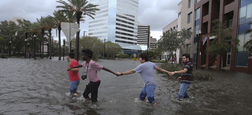 Four people link arms as they explore the flooded Jacksonville Landing in the wake Hurricane Irma on Monday, Sept. 11, 2017, in Jacksonville, Fla. 