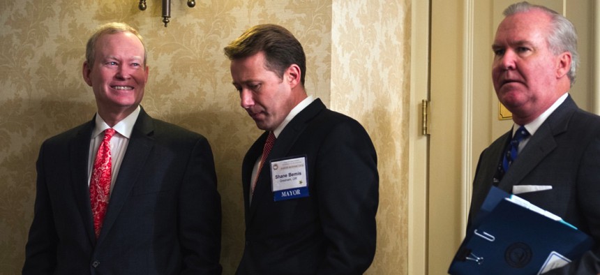 The U.S. Conference of Mayors' former president, Oklahoma City Mayor Mick Cornett, left, and Gresham, Oregon Mayor Shane Bemis, center, wait for a news conference to begin in Washington, D.C. in Jan. 2016.