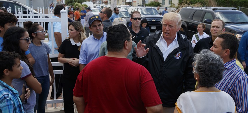 President Donald Trump talks with residents during a tour a neighborhood impacted by Hurricane Maria, Tuesday, Oct. 3, 2017, in Guaynabo, Puerto Rico.