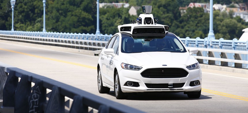 Uber employees test a self-driving Ford Fusion hybrid car, in Pittsburgh, during August 2016.