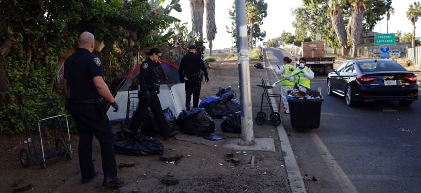 Police officers remove a tent left by the homeless during efforts to sanitize neighborhoods to control the spread of hepatitis A, in San Diego.