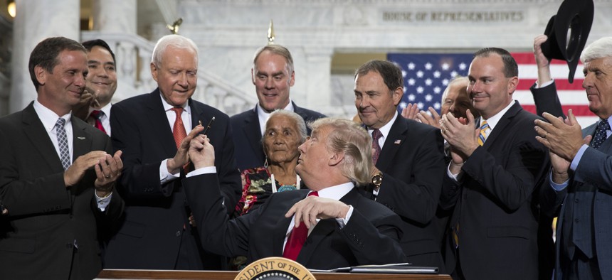 President Donald Trump hands a pen to Sen Orrin Hatch, R-Utah, after signing a proclamation to shrink the size of Bears Ears and Grand Staircase Escalante national monuments, Monday, Dec. 4, 2017, in Salt Lake City. 