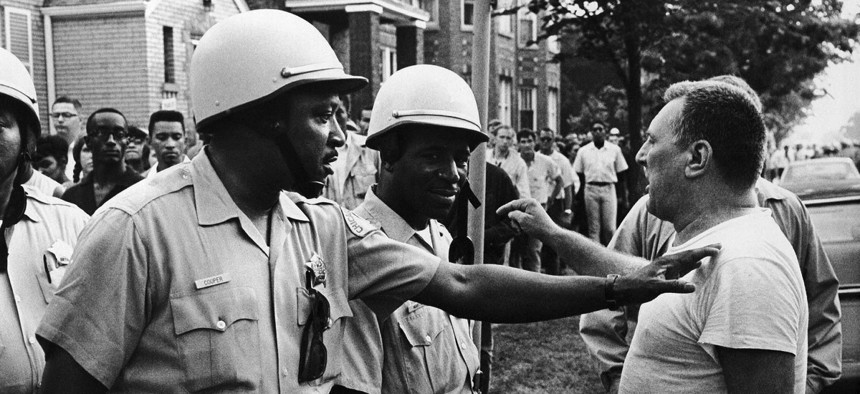 Chicago Policeman Eddie Cooper (left), places his hand on the shoulder in a restraining action of an unidentified man who protested a civil rights march in the Chicago area, Aug. 22, 1966.