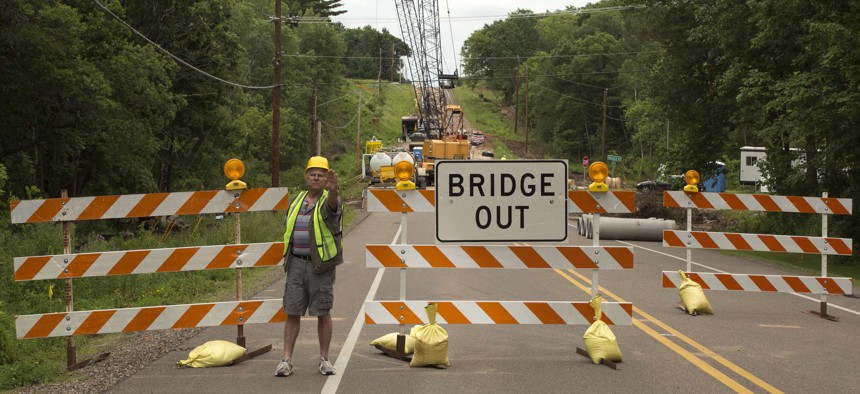 A highway worker directs traffic around a bridge under construction in River Falls, Wisconsin, during August 2016.