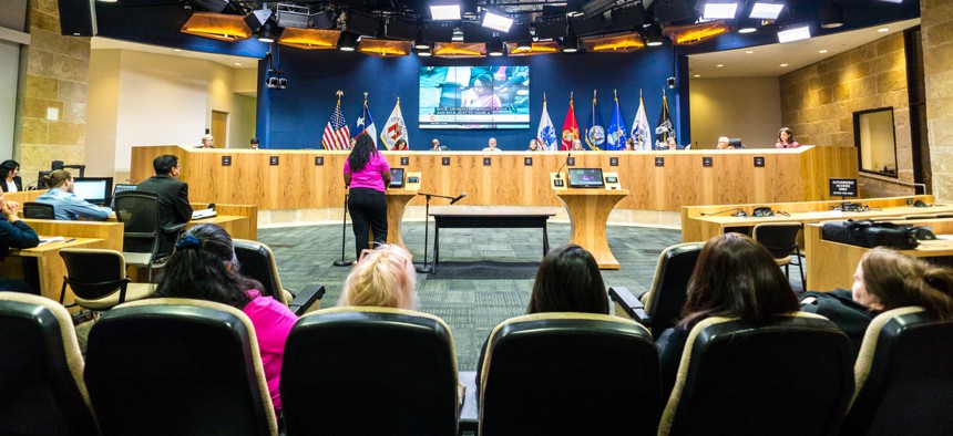 A public meeting in the chambers of the Austin City Council.