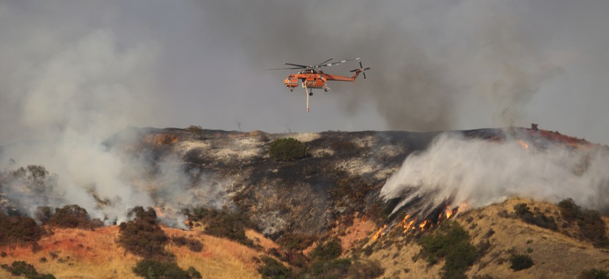 An Erickson Air-Crane helicopter flies between flames of the La Tuna Fire in Los Angeles in September 2017.