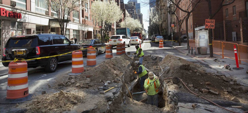 Utility workers dig in a street as they replace an aging water main, Tuesday, April 5, 2016, in New York.