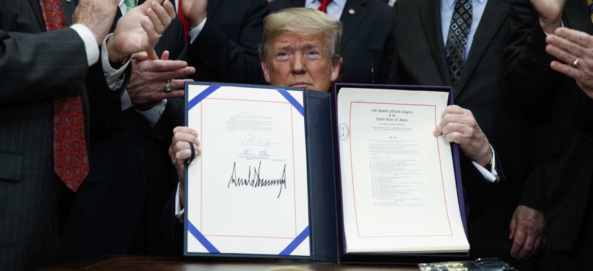 President Donald Trump shows off the "Economic Growth, Regulatory Relief, and Consumer Protection Act," in the Roosevelt Room of the White House, Thursday, May 24, 2018, in Washington.