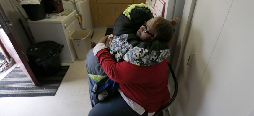 In this Jan. 29, 2016, photo, Debra Aldridge, right, hugs and recites a prayer with her grandson Mario Hendricks at her Chicago home. The number of children being raised by grandparents has spiked in recent years.