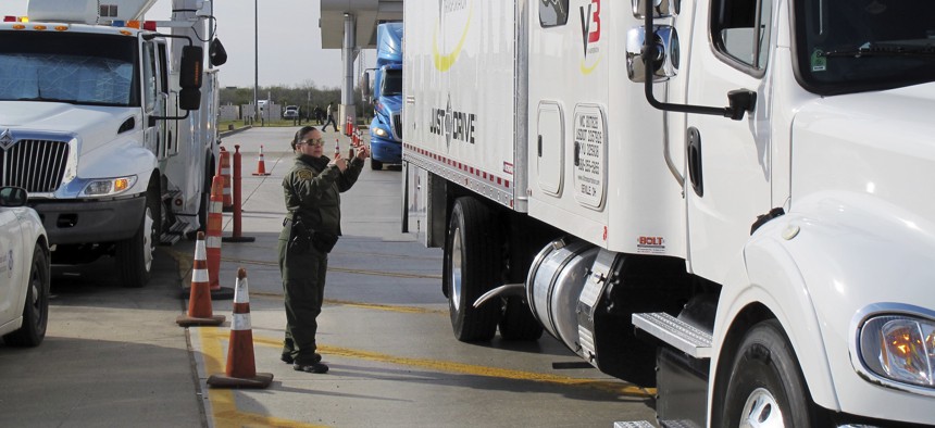 Border Patrol agent Gracie Briones waves through a tractor-trailer after it passed through an X-ray machine at the Laredo North checkpoint in Laredo, Texas, on Friday, February 2, 2018.