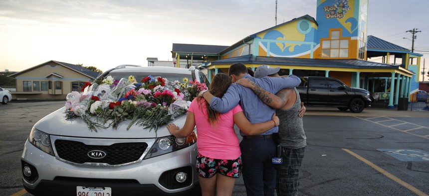 People pray by a car thought to belong to a victim of Thursday's boating accident before a candlelight vigil in the parking lot of Ride the Ducks Friday, July 20, 2018, in Branson, Mo. Seventeen people died when the boat capsized.