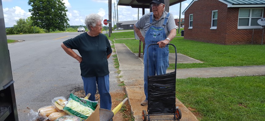 Nellie Allen, 81, left, and O’Neal West, 78, of Hackleburg, Alabama, load donated groceries into a wheelbarrow and a makeshift hand truck. They get food from the West Alabama Food Bank’s mobile pantry every two weeks.